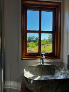 La salle de bains est pourvue d'une grande baignoire en pierre devant une fenêtre. dans l'établissement Robins Retreat - orchard with hot tub - see extras, à Alfriston