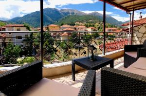 a balcony with tables and chairs and a view of mountains at Ozymandias Attic - Kalavrita in Kalavrita