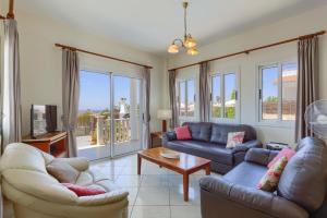 a living room with two couches and a tv at Villa Camelia by Villa Plus in Peyia