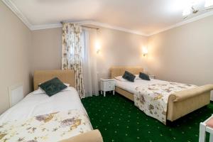 two beds in a room with green carpet at Hanul lui Mihai in Răstoaca