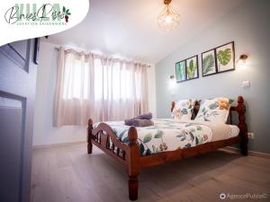 a bedroom with a bed with a wooden frame at Villa Baies Roses - Piscine chauffée Ile de la Réunion in Le Tampon