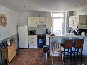 una cocina con armarios blancos, encimera y sillas en Les Embruns Méloriens, en Saint-Méloir-des-Ondes