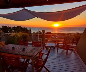 een houten terras met tafels en stoelen en een zonsondergang bij Rinconada del Mar in Punta del Este