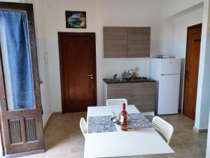cocina con mesa blanca, sillas y nevera en Aeolian Sea House, en Santa Marina Salina