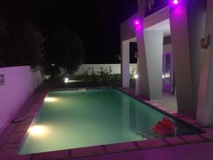 a swimming pool lit up at night with purple lights at Magnifique villa avec piscine sur l’île de Djerba pour vacances in Arkou