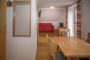 uma sala de estar com uma mesa e um sofá vermelho em Hotel im Sonnental em Jachenau