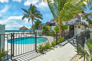 a house with a swimming pool and palm trees at Seaside At Anna Maria Island Inn in Bradenton Beach