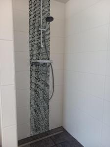 La salle de bains est pourvue d'une douche et de carrelage blanc. dans l'établissement Stal Zwartschaap, à Stuifzand
