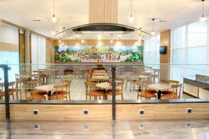 a restaurant with tables and chairs and a painting on the wall at Cordia Hotel Banjarmasin - Hotel Dalam Bandara in Banjarbaru