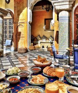 een tafel gevuld met borden voedsel op een tafel bij Riad Layalina Fes 7 Chambres & 18 Personnes Piscine, Parking, Vue & Wifi au Pied Medina in Fès