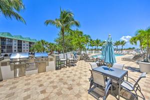 a patio with tables and chairs and a grill and palm trees at Naples Escape in Regatta with Resort Amenities! in Naples