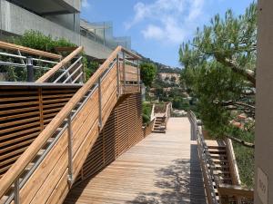 una pasarela de madera que conduce a un edificio en SARA RIVIERA Costa Plana en Cap d'Ail