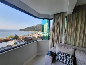 a room with a balcony with a view of the ocean at 3 Suítes Linda Vista da Orla de BC a 50m da Praia in Balneário Camboriú
