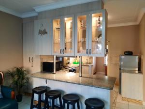 a kitchen with white cabinets and bar stools at Uvongo square Unit 24 in Uvongo Beach