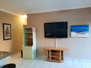 sala de estar con TV de pantalla plana en la pared en Uvongo square Unit 24, en Uvongo Beach