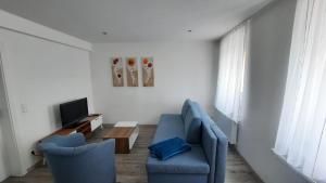 Hainichen的住宿－Fewo Böhle in Hainichen，客厅配有2把蓝色椅子和电视