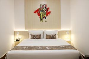 a bedroom with a bed with a painting on the wall at Cordia Hotel Banjarmasin - Hotel Dalam Bandara in Pulaubiruang