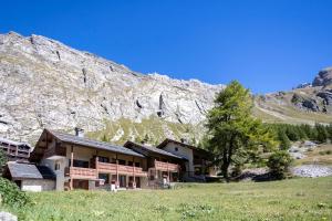 a building in a field next to a mountain at Appartement esprit chalet - splendide vue montagne in Val-d'Isère