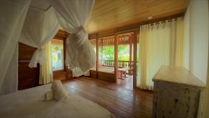 a bedroom with a bed and wooden floors and windows at Palm Green Hotel in Kuta Lombok