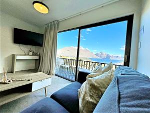 a living room with a blue couch and a large window at Magic mountain Vista in Queenstown