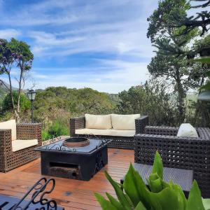 a patio with a couch and a fire pit at Chalés Mirante Monte Verde in Monte Verde