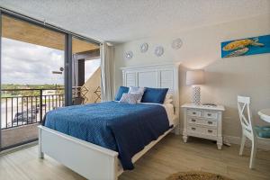 Aloha Hibiscus Room,Sunset Views - Hawaiian Inn Beach Resort في Daytona Beach Shores: غرفة نوم بسرير وشرفة