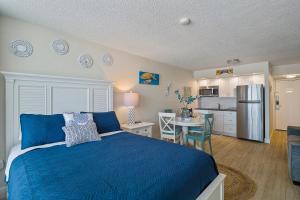 Aloha Hibiscus Room,Sunset Views - Hawaiian Inn Beach Resort في Daytona Beach Shores: غرفة نوم بسرير ازرق ومطبخ
