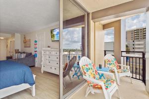 Aloha Hibiscus Room,Sunset Views - Hawaiian Inn Beach Resort في Daytona Beach Shores: غرفة نوم بسرير وكراسي وشرفة