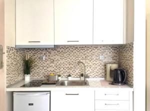 una cucina con armadi bianchi e lavandino di Emerald Mini Suite:Your deluxe studio in Kalamaria a Salonicco