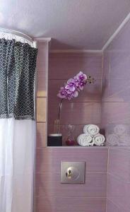 La salle de bains est pourvue d'une étagère avec des fleurs violettes et des serviettes. dans l'établissement 4 Travelers, à Thessalonique