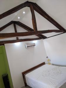 a bedroom with a white bed with wooden beams at Serendipity Cottage Palamartsa in Palamarca