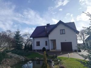una casa bianca con un laghetto davanti di Noclegi, agroturystyka, pokoje a Konstantynów