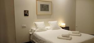 Un dormitorio con una cama blanca con toallas. en Apartamentos Arquitas, en Mérida