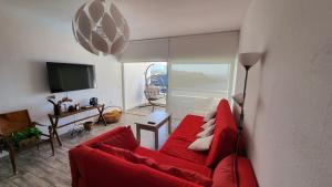 a living room with a red couch and a television at En Primera línea de mar y piscina - Apartamento AZUR - El Ancla - Callao Salvaje - COSTA ADEJE in Callao Salvaje