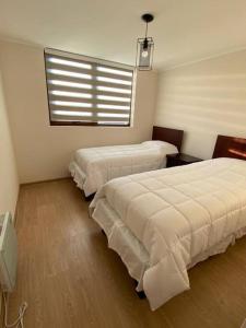 ein Schlafzimmer mit zwei Betten und einem Fenster in der Unterkunft Departamento en Villarrica a pasos del Lago in Villarrica