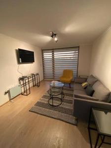 ein Wohnzimmer mit Sofa und Tisch in der Unterkunft Departamento en Villarrica a pasos del Lago in Villarrica