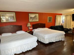 two beds in a hotel room with orange walls at Great House Motel in Sequim