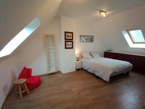 een slaapkamer met een bed en een rode stoel bij DOMAINE DES TISSEYS vue sur le Mont St Michel in Dragey