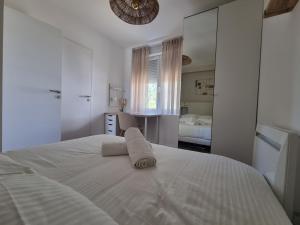 1 dormitorio con 1 cama blanca grande y toallas. en Le Coco Madame by Madame Conciergerie, en Bruz