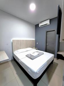 a bedroom with a white bed and a blue wall at HOTEL NABU DEL PACIFICO in Tumaco