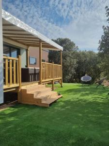 une maison avec une terrasse en bois et une table sur l'herbe dans l'établissement Charmant et Spacieux Mobil Home, à Rocbaron