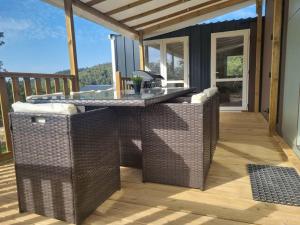 a patio with a table and wicker chairs on a deck at Charmant et Spacieux Mobil Home in Rocbaron