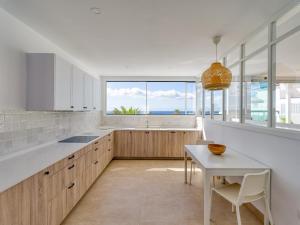 una cucina con armadi bianchi, tavolo e finestra di Pasitoblanco Porto Mare 7 Seaview Villa private heated pool a Pasito Blanco