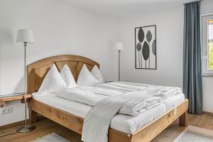 Habitación blanca con cama de madera y almohadas blancas. en Ferienwohnung Kastenmühle im Mondseeland, en Guggenberg