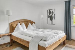 a white bedroom with a wooden bed with white pillows at Ferienwohnung Kastenmühle im Mondseeland in Guggenberg