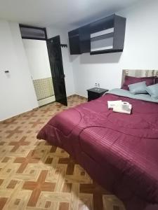 a bedroom with a large bed with a purple comforter at Hotel Villa Real in Bogotá