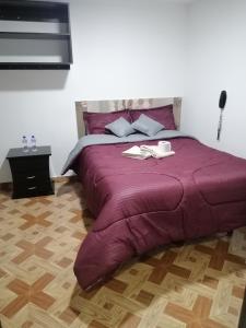 a large bed with a purple comforter in a bedroom at Hotel Villa Real in Bogotá