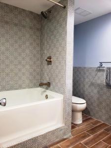 La salle de bains est pourvue d'une baignoire blanche et de toilettes. dans l'établissement 1400sf self checkin modern chalet AC Grill Firepit, à Thornhurst