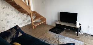a living room with a couch and a flat screen tv at l'Aurore Dorée, duplex rénové - parking privé - wifi gratuit in Saint-Quentin