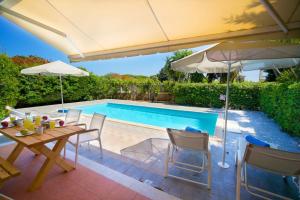 un patio con mesa, sombrilla y piscina en Villa Roza en Skala Kefalonias